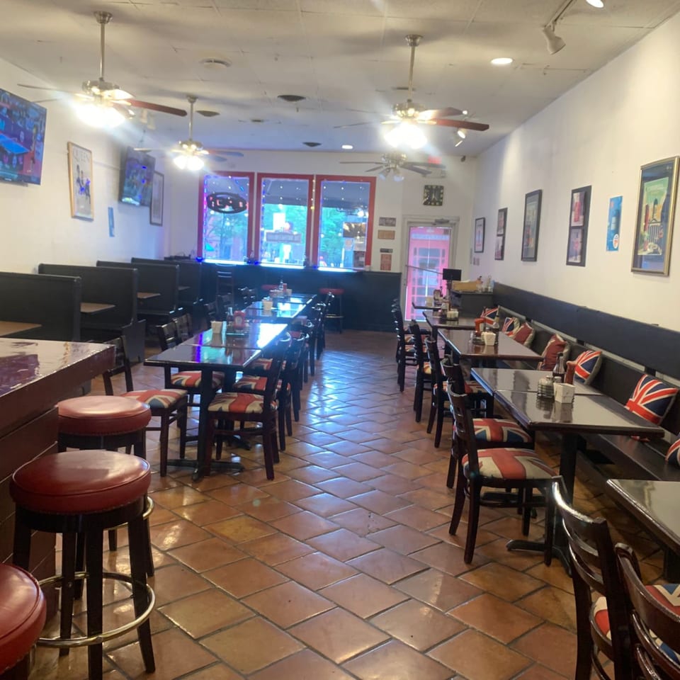 Interior of The British Embassy Fish and Chips, featuring tables, booths, and chairs with Union Jack upholstery.